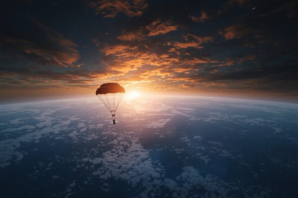 NASA Artemis II spacecraft capsule with parachutes descending toward the Pacific Ocean at sunset