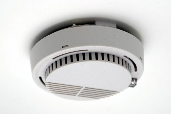 White ceiling-mounted smoke detector with indicator LED visible at a low angle
