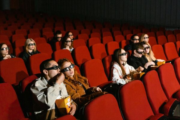 Crowded modern movie theater audience watching a film on a glowing big screen, May 2026 cinema atmosphere