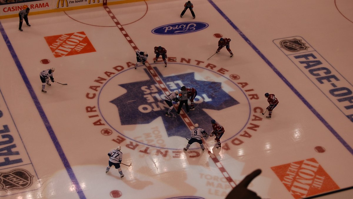 Hockey players competing for the puck at faceoff during a high-stakes playoff game