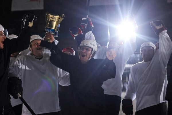 Hockey team celebrating championship victory on ice rink with trophy