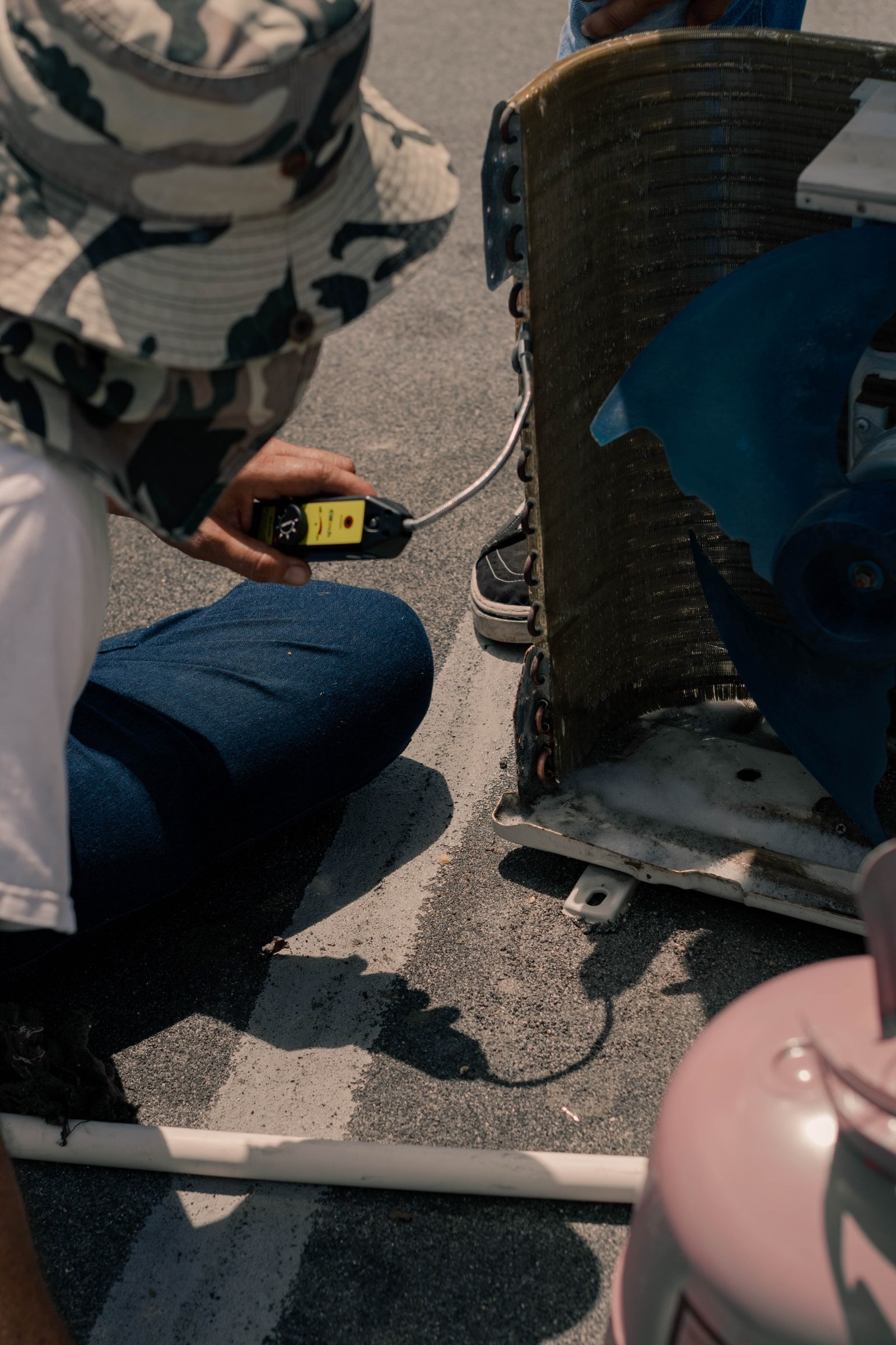 Technician testing an outdoor AC condenser unit with a multimeter to find why it is not cooling