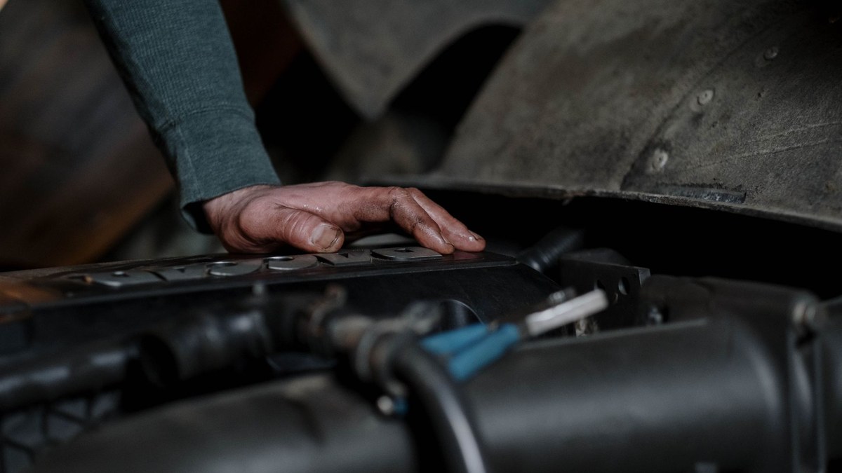 Technician inspecting engine to diagnose car air conditioner not cold