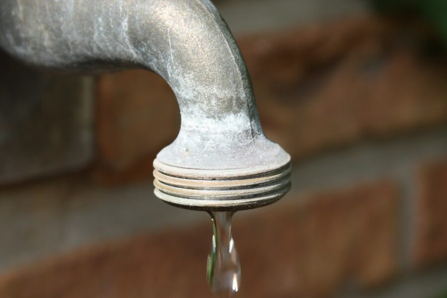 Dripping faucet with a water droplet about to fall — a worn cartridge or washer is the usual cause