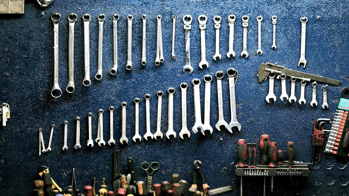 Water heater repair tools including wrench thermocouple and pliers on workshop bench