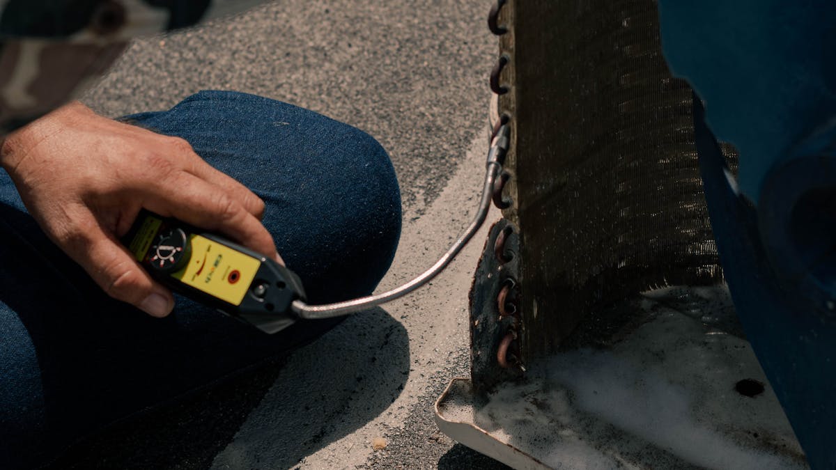 Close-up of a technician cleaning and servicing an air conditioner unit with tools