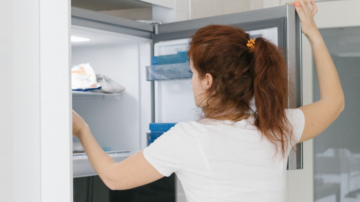Person opening refrigerator door to check why it is not cooling