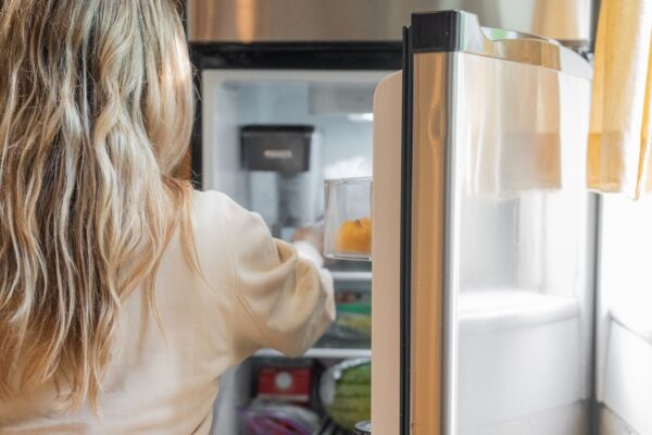 Woman checking food in a refrigerator that is not cooling properly