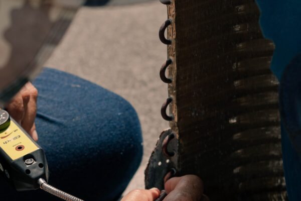 Technician using a leak detector on a frozen air conditioner evaporator coil showing ice buildup